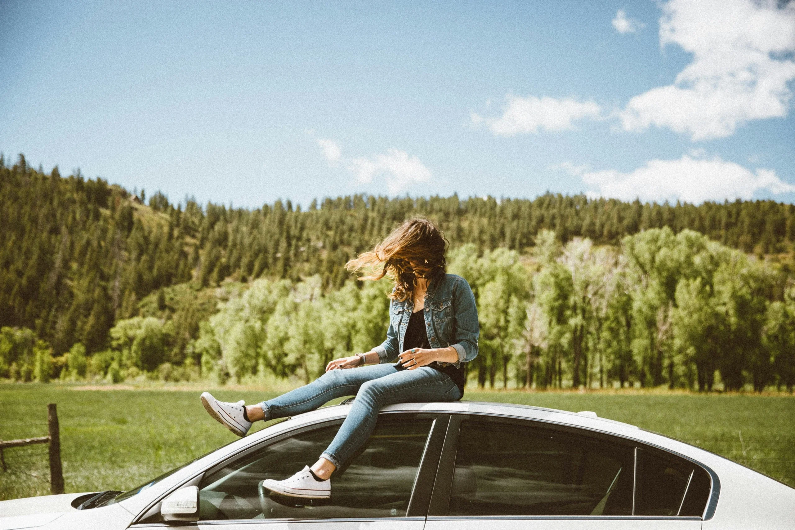 woman having fun on the roof of her car with the wind blowing in her hair