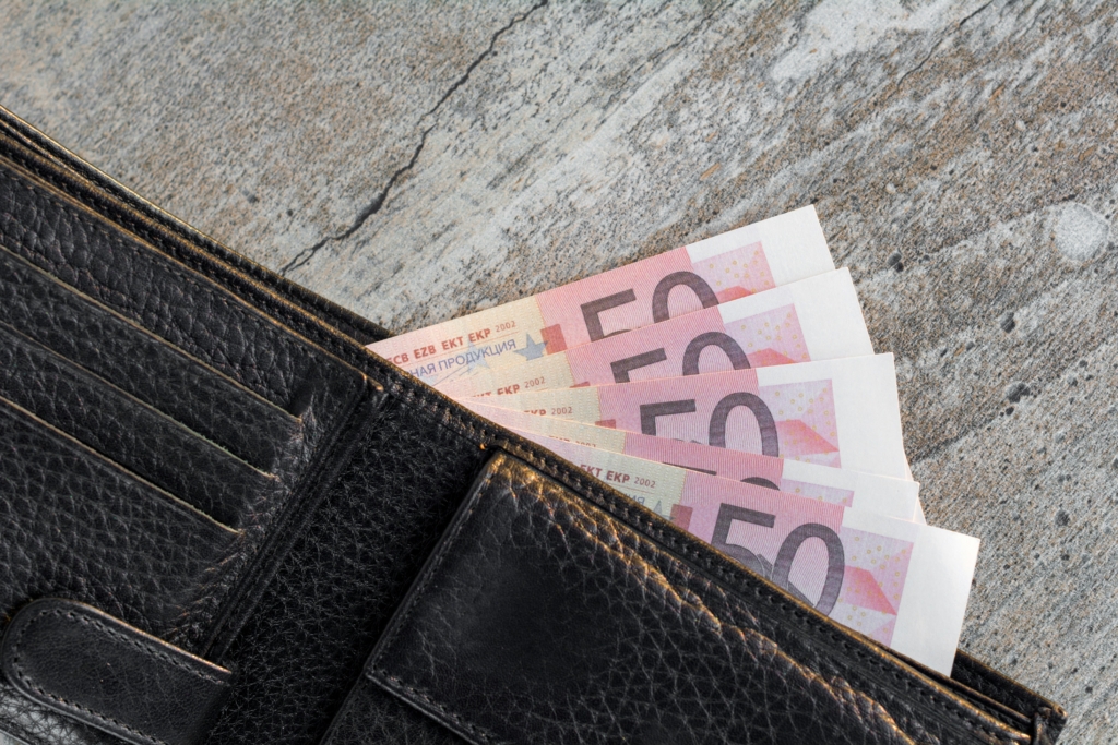 an otherwise empty brown leather wallet displaying a number of fifty-dollar bills